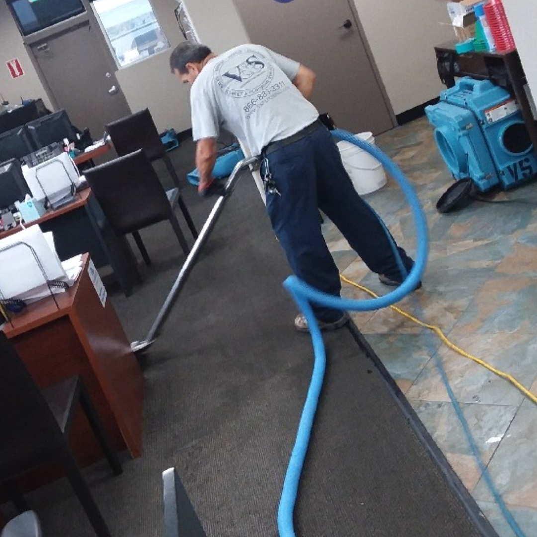 A man using a professional carpet cleaning machine in an office environment.